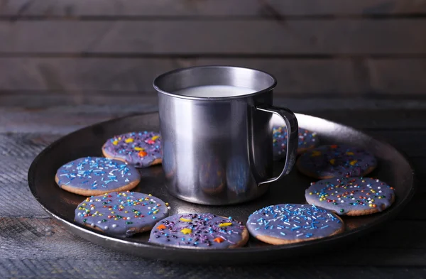 Biscotti smaltati su vassoio di metallo con tazza di latte su fondo rustico di assi di legno — Foto Stock