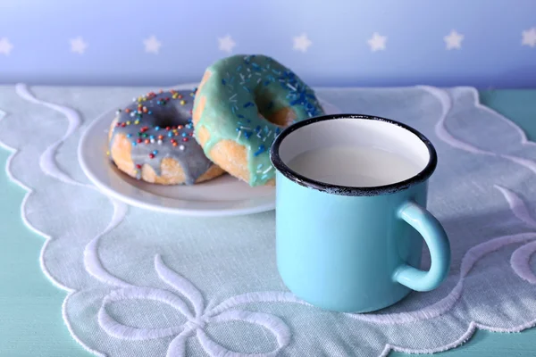 Glazed donuts with cup of milk on napkin and color dots background — Stock Photo, Image
