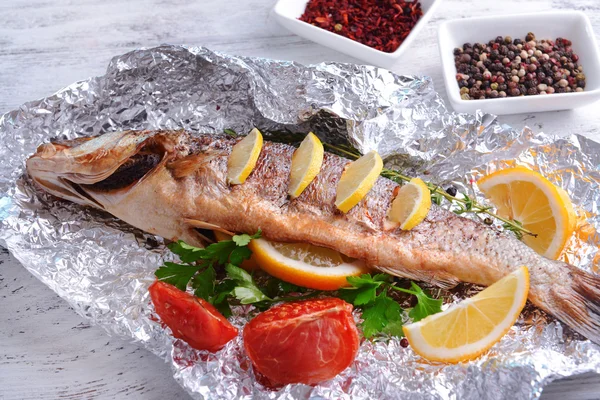 Peixe cozido no forno saboroso em folha na mesa close-up — Fotografia de Stock