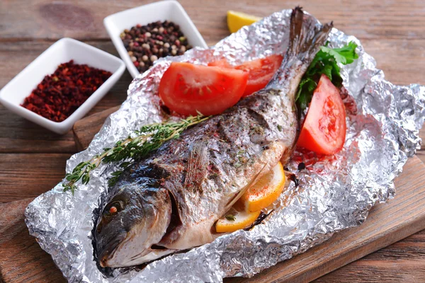 Pesce al forno saporito in lamina di metallo su tavolo primo piano — Foto Stock