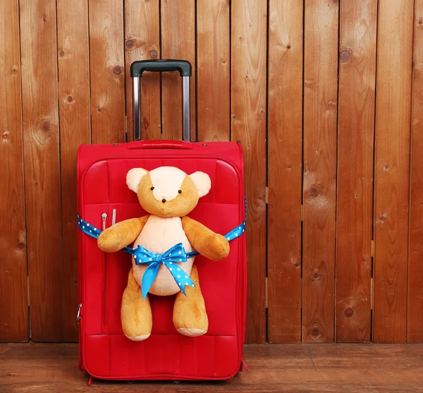 Suitcase with teddy bear on wooden planks background — Stock Photo, Image