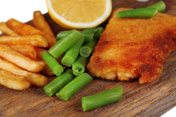 Breaded fried fillet and potatoes with asparagus and sliced lemon on wooden cutting board background — Stock Photo, Image