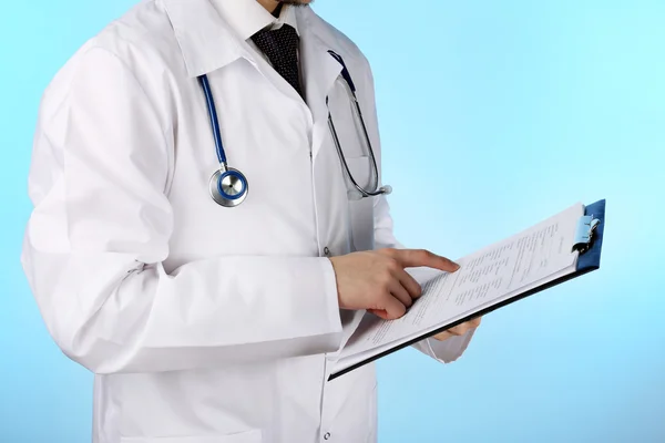 Arzt arbeitet mit Dokumenten auf blauem Hintergrund — Stockfoto