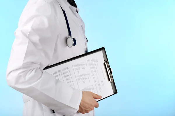 Médico trabajando con documentos sobre fondo azul — Foto de Stock