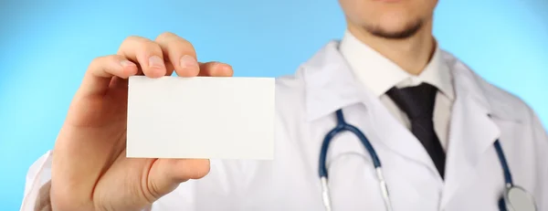 Médico masculino con tarjeta sobre fondo azul — Foto de Stock