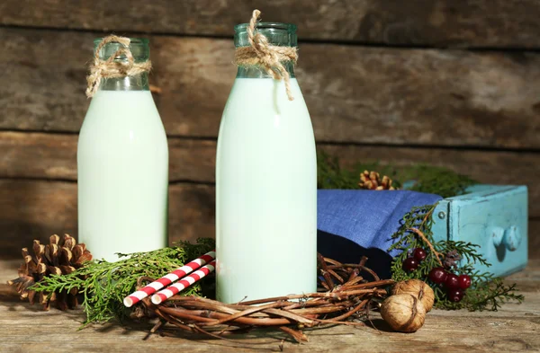 Flaskor av färsk mjölk med naturlig inredning, på trä bakgrund — Stockfoto