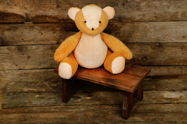 Bear toy on bench on wooden background — Stock Photo, Image