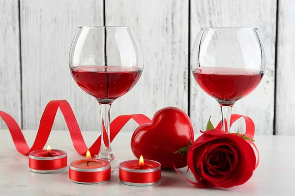 Composición con vino tinto en vidrio, rosas rojas y corazón decorativo sobre fondo de madera de color —  Fotos de Stock