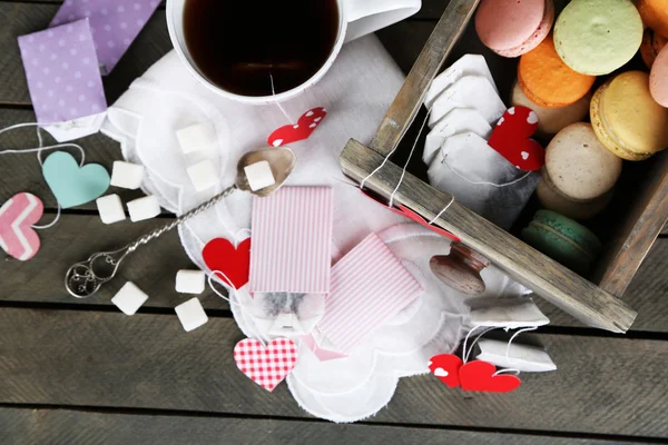 Coração em forma de etiquetas de teca, macaroons e xícara de chá no fundo de madeira — Fotografia de Stock