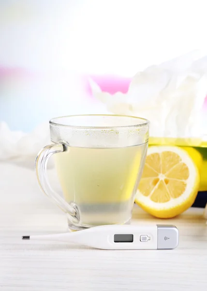 Heißer Tee gegen Erkältungen, Tabletten und Taschentücher auf Tisch vor hellem Hintergrund — Stockfoto