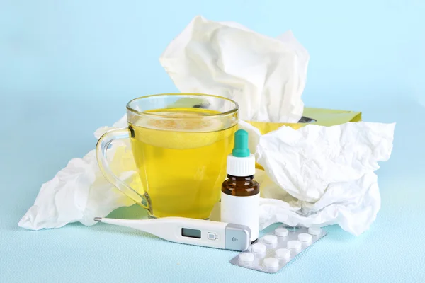 Chá quente para resfriados, medicamentos e lenços no fundo azul — Fotografia de Stock