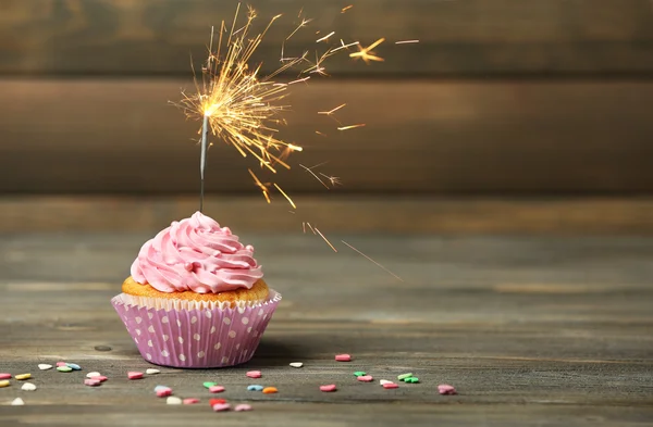 Cupcake mit Wunderkerze auf Tisch auf Holzgrund — Stockfoto