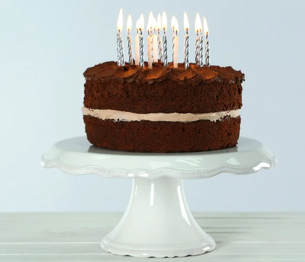 Delicioso pastel de chocolate con velas en la mesa sobre fondo claro —  Fotos de Stock