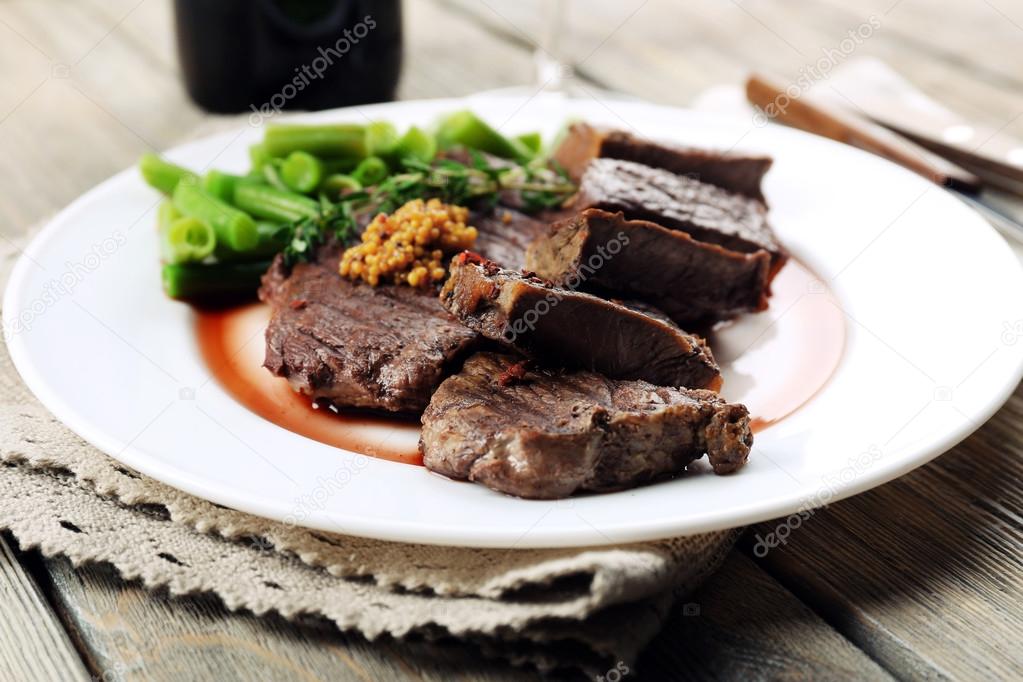 Steak with wine sauce on plate on wooden table