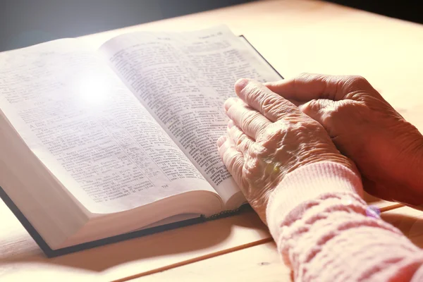 Handen van oude vrouw met Bijbel op tafel, close-up — Stockfoto