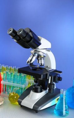 Mikroskop, tanecikler ve test tüpleri masada, renk arkaplanında