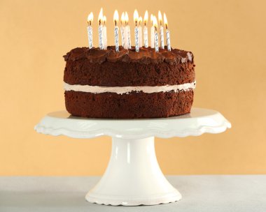 Bej renkli arka plan üzerinde masada mumlarla lezzetli çikolatalı kek