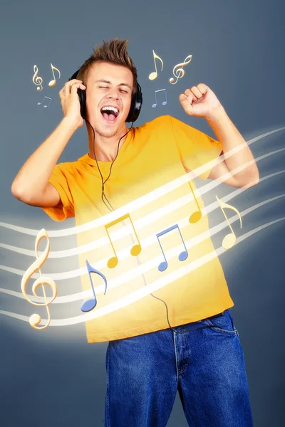 Jeune homme avec écouteurs écoutant de la musique sur fond gris — Photo