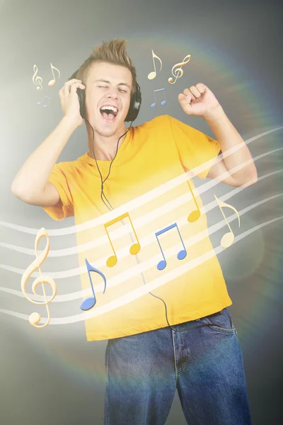 Junger Mann mit Kopfhörern hört Musik auf hellem Hintergrund — Stockfoto
