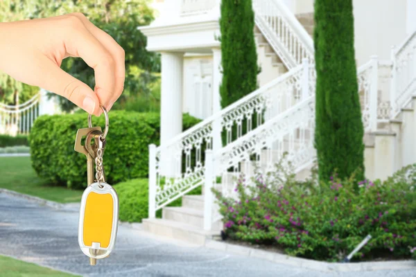 Llave en mano en el fondo de la casa, concepto de bienes raíces — Foto de Stock