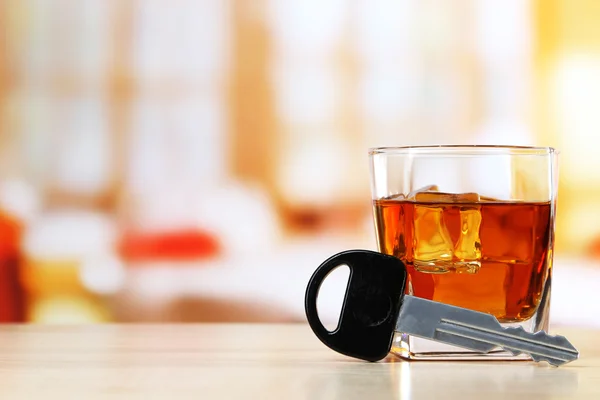 Composición con llave de coche y vaso de whisky, sobre mesa de madera, sobre fondo brillante — Foto de Stock