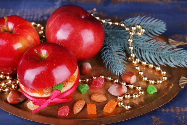 Christmas red apples stuffed with dried fruits on metal tray on color wooden table background — Stock Photo, Image