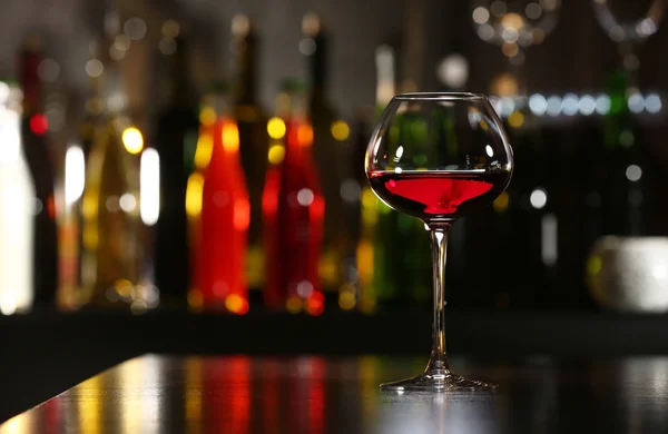 Glass of wine with bar on background — Stock Photo, Image