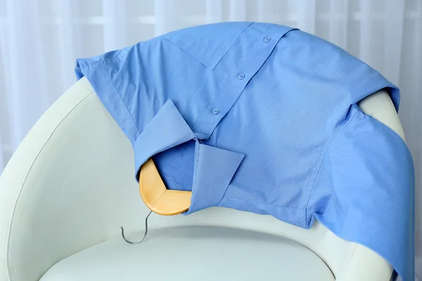 Camicia blu su sedia su sfondo tenda — Foto Stock