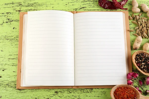 Specerijen met recept boek op kleur houten tafel achtergrond — Stockfoto