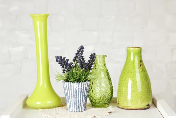 Interior with decorative vases and plant on table top and white brick wall background — Stockfoto