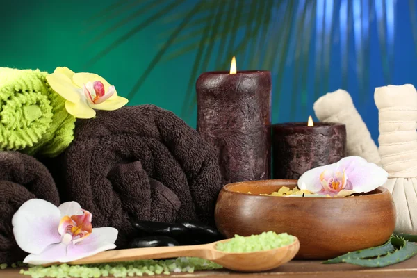 Wellness-Behandlungen mit Orchideenblumen auf Holztisch vor buntem Hintergrund — Stockfoto