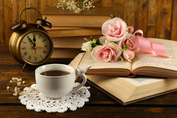 Tasse de thé avec livres et fleurs sur fond en bois — Photo