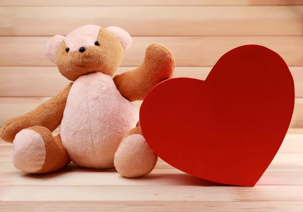 Oso de peluche con corazón rojo sobre fondo de madera —  Fotos de Stock