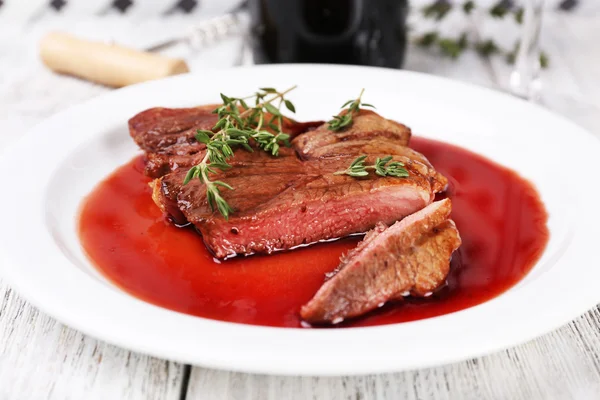 Bife com molho de vinho na placa na mesa de madeira — Fotografia de Stock