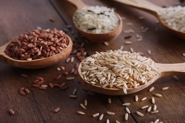 Различные виды риса в ложках на деревянном фоне — стоковое фото