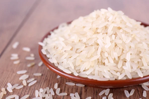 Grain of rice on plate on wooden background — Stock Photo, Image