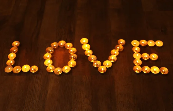 Woord liefde gevormd door kaarsen branden op donkere achtergrond — Stockfoto