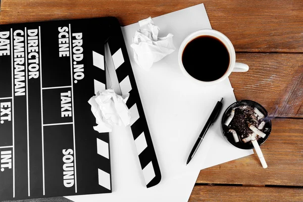 Movie clapper with cup of coffee and ashtray with cigarette butts — Stock Photo, Image