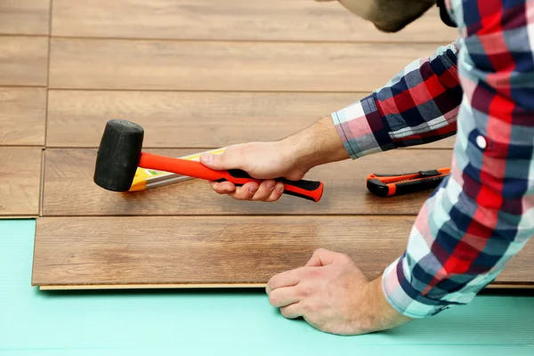 Trabalhador de carpinteiro instalando piso laminado na sala — Fotografia de Stock