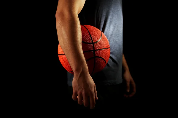 Basketball player holding ball, on dark background — Stock Photo, Image
