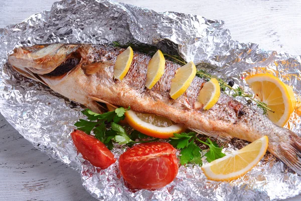 Tasty baked fish in foil on table close-up — Stock Photo, Image