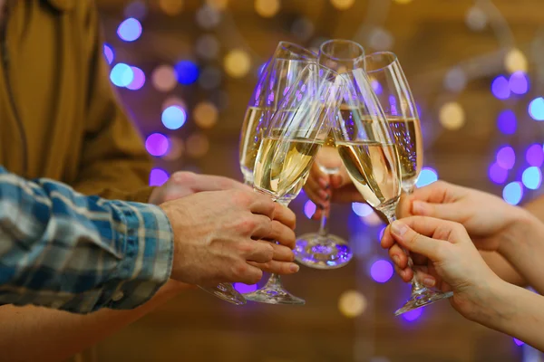 Clinking copos de champanhe nas mãos sobre luzes brilhantes fundo — Fotografia de Stock