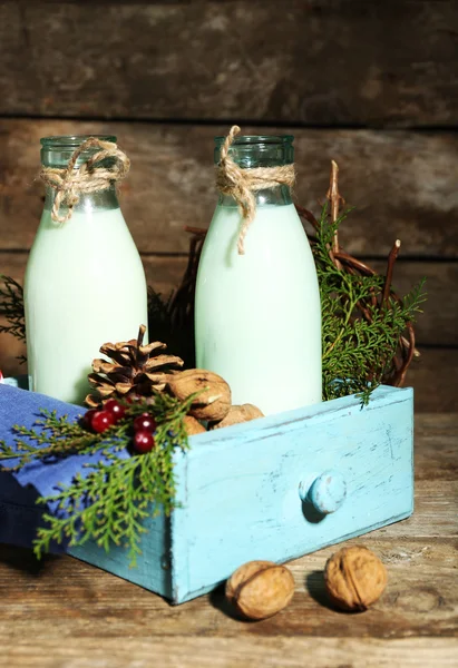 Üveg friss tejet, természetes díszítéssel, fából készült háttér — Stock Fotó