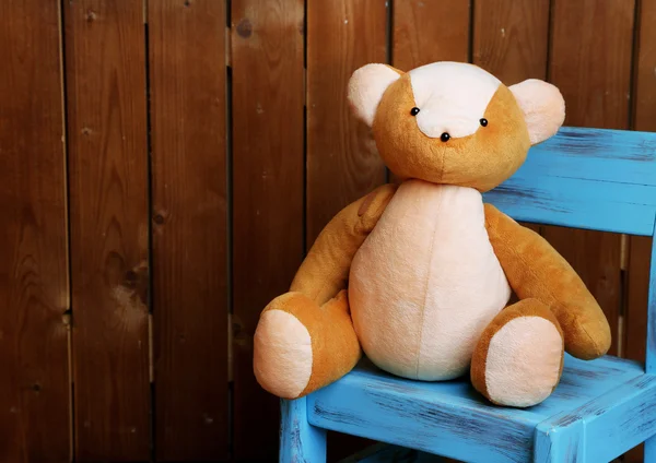 Медвежья игрушка на стуле на деревянном фоне — стоковое фото