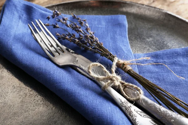 Silberbesteck gebunden mit Seil auf Metalltablett mit bunter Serviette und getrockneter Blume auf Holzplanken Hintergrund — Stockfoto