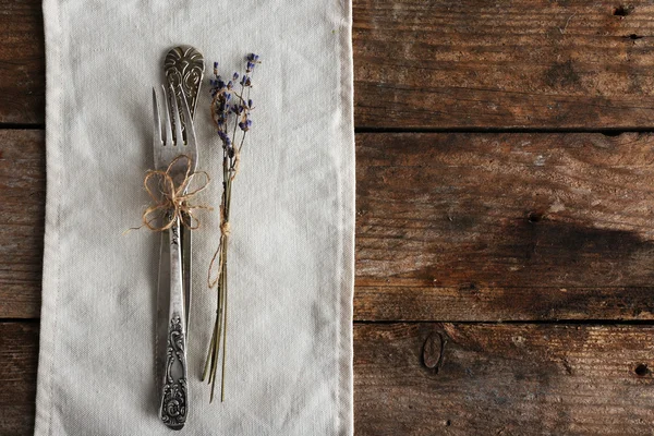 Silverware tied with rope on white fabric with dried flower on wooden planks background — Stock Photo, Image