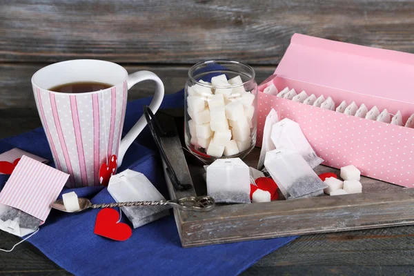 Hjärtformade teabag Taggar, box och kopp te på trä bakgrund — Stockfoto