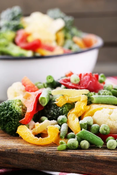 Verduras congeladas sobre tabla de cortar, sobre servilleta, sobre fondo de mesa de madera —  Fotos de Stock