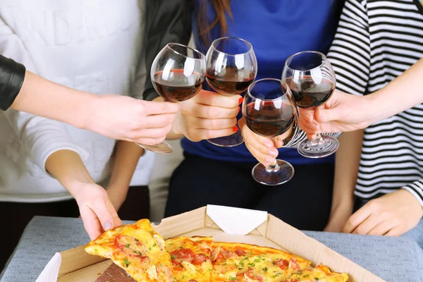 Friends hands with glasses of wine and pizza, close up