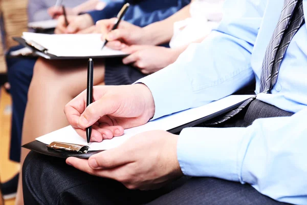 Manos sosteniendo bolígrafos y tomando notas en la conferencia — Foto de Stock